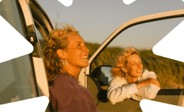 Two women smiling by a car, representing life insurance cover